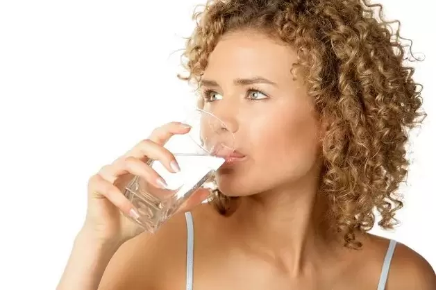 Dziewczyna stosuje dietę dla leniwych, popijając szklankę wody przed jedzeniem